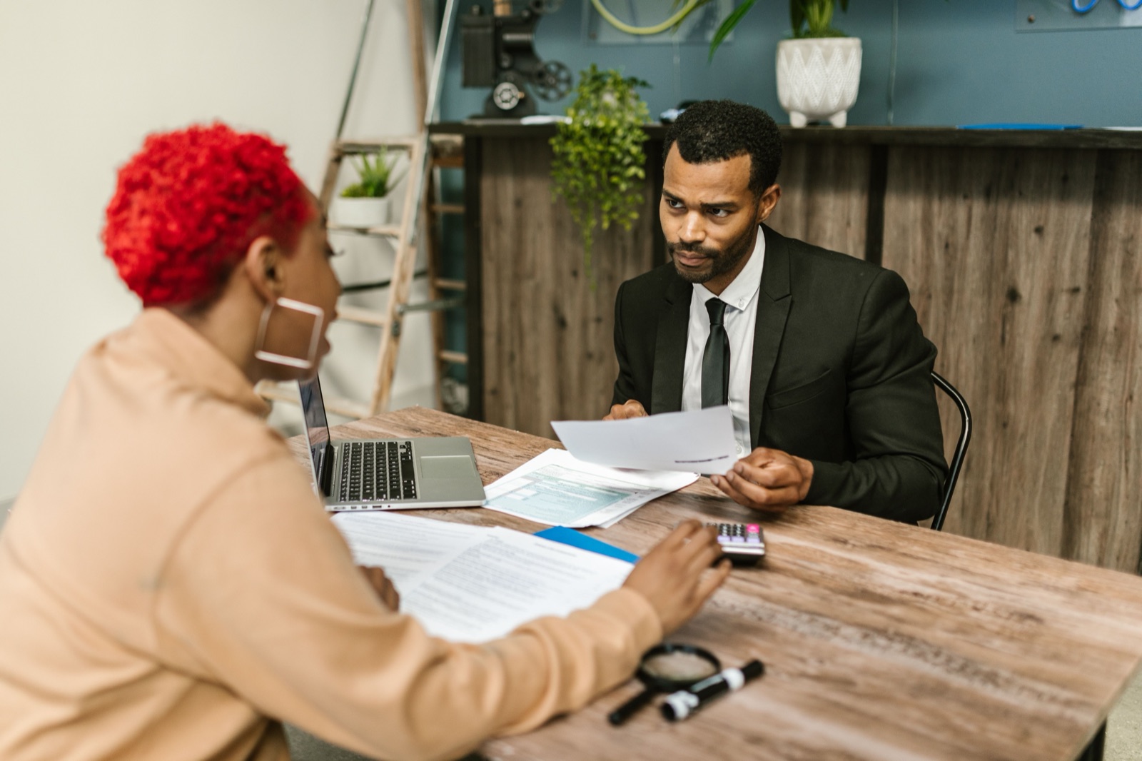 Two people reviewing financial paperwork at a desk during a bookkeeping conversation.